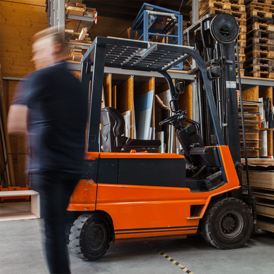 Man standing next to forklift in warehouse